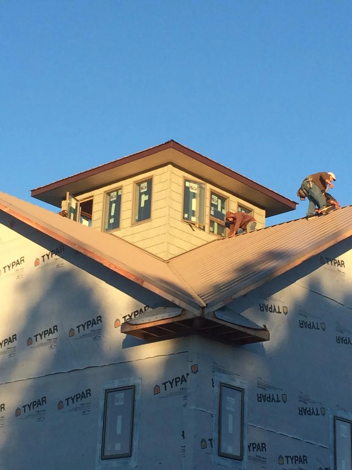 Roofers working around a rooftop cupola on a new metal roof at sunset — Roof Waterproofing in Fresno by Roofing Brothers